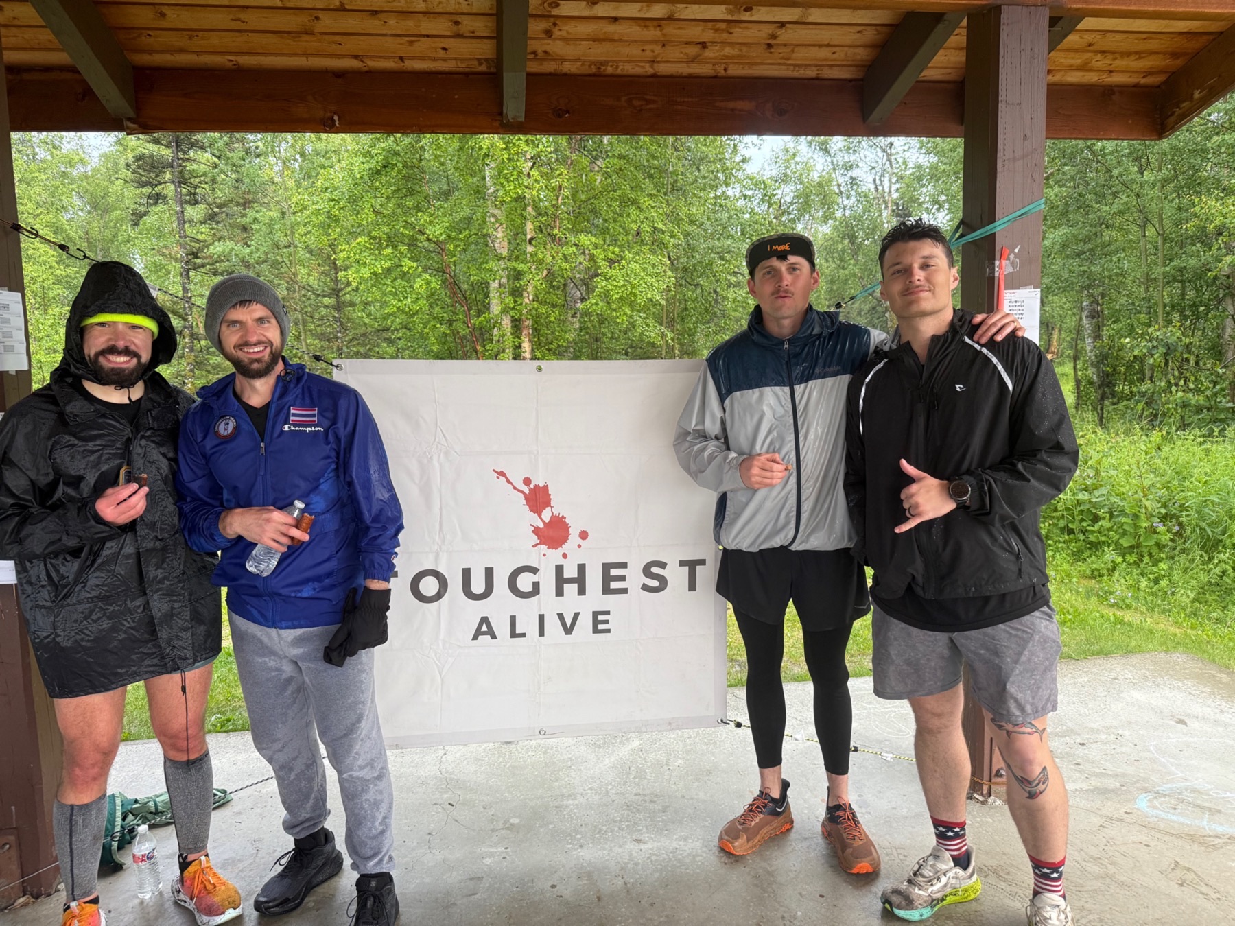 Four Hourglass participants standing together beside a Toughest Alive banner.